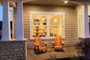 The front of a home featuring columns and two rocking chairs in front a large double-hung windows.