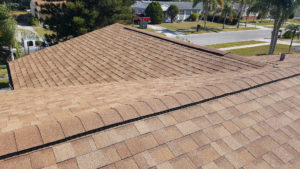 A close-up of a light-brown asphalt shingle roofing system.