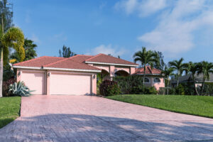 A single-story home in Florida with a two-car garage, paver driveway, and tile roof.