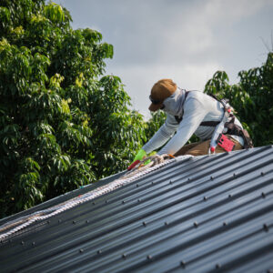 A roofer installs metal standing seam roofing on a residential home.
