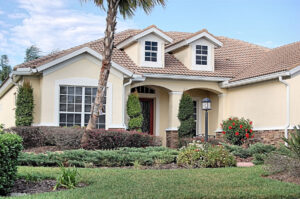 A house in Florida has a palm tree in the front yard and features stucco siding and a clay tile roof.