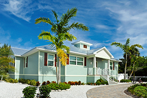 A beautiful Florida home with palm trees out front, light blue siding, and a metal roofing system.