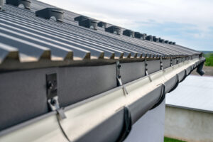 A close-up image of a the edge of a standing-seam metal roofing systems with half-round gutters.