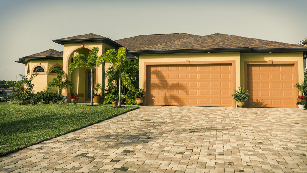 A modern Florida home with a paver driveway, three-car garage, and new asphalt shingle roofing.