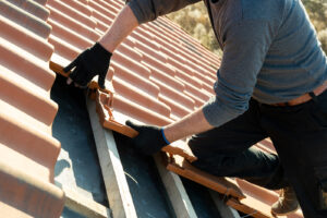 A worker installs roofing tiles.