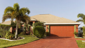 A florida home with palm trees in the yard features a beige shingle roof.